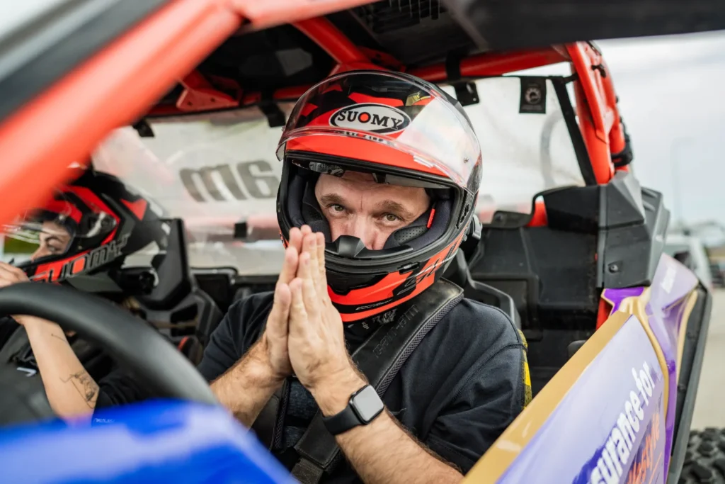 Portretas: Vairuotojas su šalmu, rankos maldos poza.